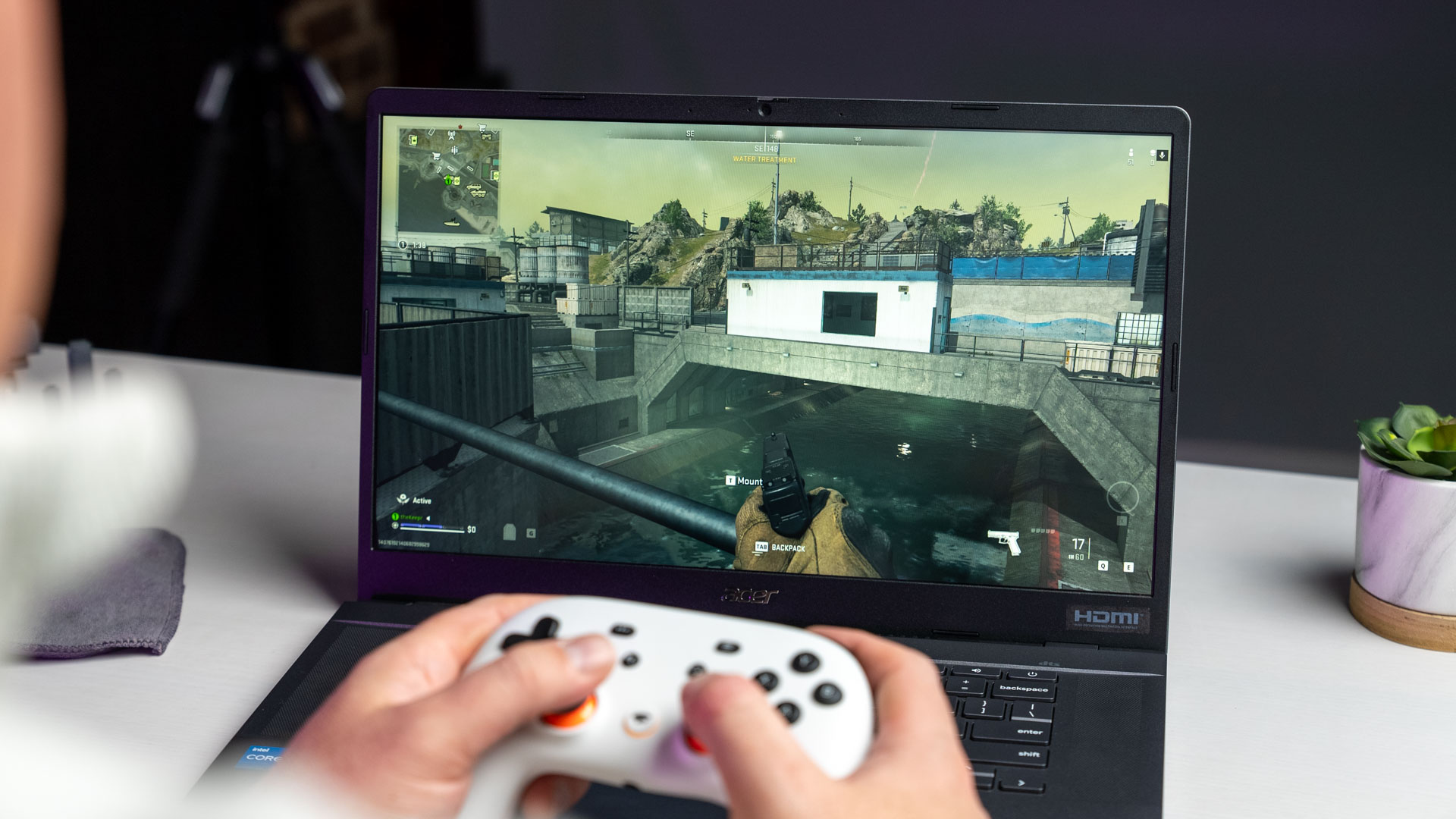 Persona jugando un videojuego de disparos en una laptop con un control
